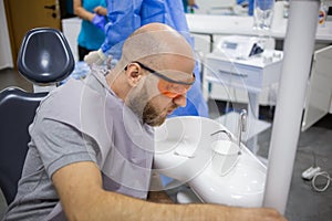 Caucasian male is rinsing his mouth during a wisdom tooth extraction surgery in a dental hospital