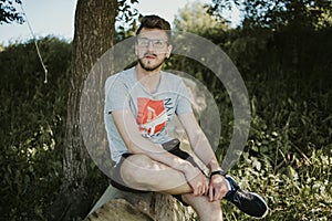 Caucasian male sitting on a tree slog photo