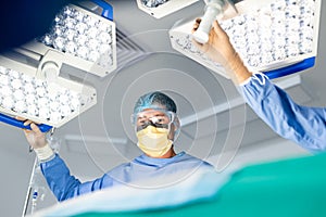 Caucasian male surgeon adjusting lights with colleague in operating theatre