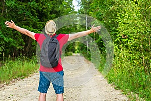 Caucasian male tourist in forest with arms wide open. Copy space.Man backpacker arms outstretched in forest.Summer day