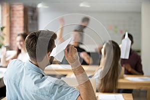 Caucasian male worker launching paper plane in office