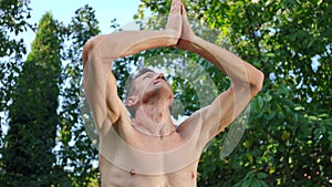 Caucasian male yogi stretching arm up with hands clasped keeping balance training. Portrait of adult fit motivated man