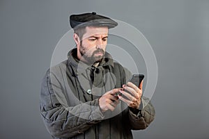 Caucasian man 35 years old with concentrated look at smartphone, studio shot. Idea - village dweller and modern technology