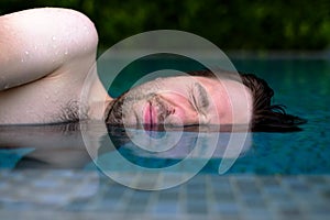 Caucasian man is afraid to swim in swimming pool. He do not like chlorine water and closes his eyes