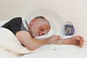 Caucasian man asleep in bed with alarm clock