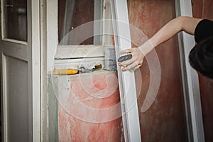 A caucasian man with a black tape tied to his injured finger washes the window frame.