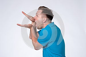 Caucasian man in blue shirt making bla bla sign with his hand