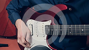 Caucasian man in a blue shirt plays an red electric guitar photo