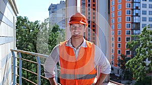 Caucasian man builder engineer in helmet and waistcoat standing on the roof on the construction site. Business, building