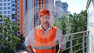 Caucasian man builder engineer in helmet and waistcoat standing on the roof on the construction site. Business, building