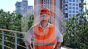 Caucasian man builder engineer in helmet and waistcoat standing on the roof on the construction site. Business, building