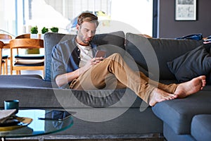 Caucasian man busy texting while sitting in a modern home