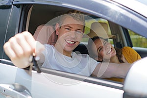 Caucasian man buying new or rent car and showing the key, sitting in car