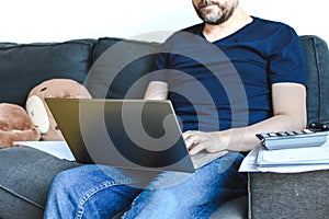 Caucasian man with casual clothing sitting in sofa and using laptop.