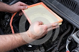 Caucasian man changing new air filter in car engine bay