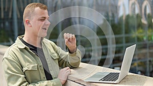 Caucasian man communicates in sign language via video link on laptop.