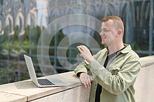 Caucasian man communicates in sign language via video link on laptop.