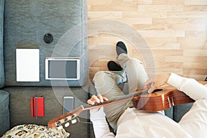 Caucasian man composing music playing a Spanish guitar in the living room. Overhead shot from above and empty copy space