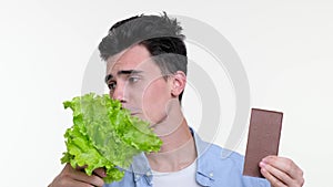 Caucasian Man Contemplating lettuce and Chocolate Bar on White Background