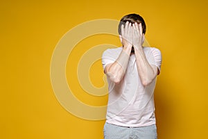 Caucasian man covered his face with his hands. He is upset, stressed and very tired. Copy space. Psychological concept.