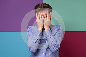 Caucasian man covering his face feeling humiliated.