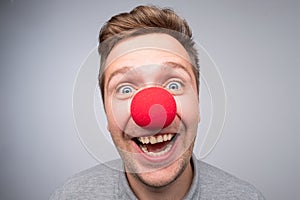 Caucasian man with crazy look wearing a clown nose