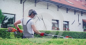 Caucasian man cutting bushes with electric hedge trimmer