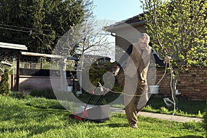 Caucasian man cutting grass. red mower