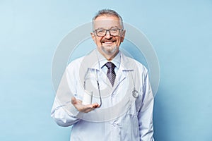 Caucasian man doctor holding bottle of pills on white background