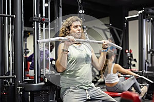 Caucasian man doing exercises on lat pull down machine in gym