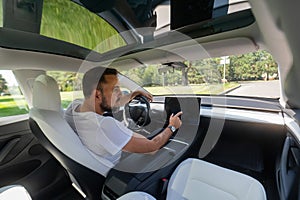 Caucasian man driving a modern electric car.