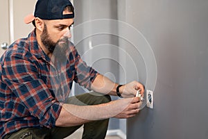 caucasian man electrician holding screwdriver working on the plug electric on residential electric system installing