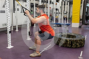 Caucasian man exercising suspension training trx at gym.