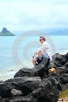 Caucasian man in forties on rocky Hawaiian shore