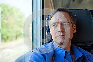 Caucasian man in forties sitting on train, commuting