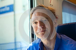 Caucasian man in forties sitting on train, commuting