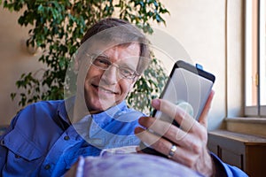 Caucasian man in forties smiling, looking at cellphone