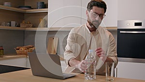 Caucasian man freelance businessman user with laptop working from home distant internet computer work at kitchen pouring