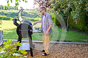 Caucasian man grilling food outdoors over a charcoal barbecue.