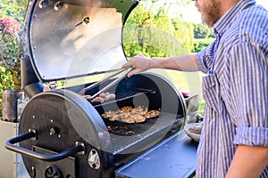 Caucasian man grilling food outdoors over a charcoal barbecue.