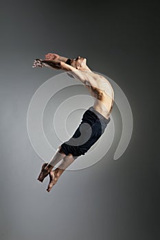 Caucasian man gymnastic leap posture on grey