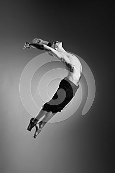 Caucasian man gymnastic leap posture on grey