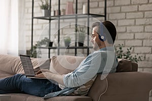 Caucasian man in headphones work on laptop at home