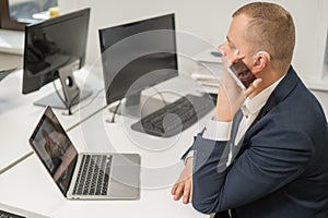Caucasian man with a hearing aid talking on the phone on speakerphone.