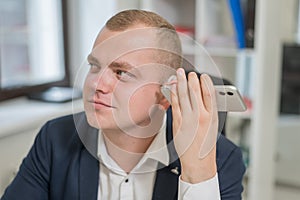 Caucasian man with a hearing aid talking on the phone on speakerphone.