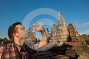 Caucasian man holding water bottle because he is thirsty and wants to drink.