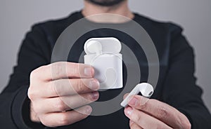 Caucasian man holding white wireless earphones