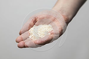 A Caucasian man holds raw long-grain rice in a hand