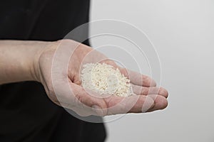 A Caucasian man holds raw long-grain rice in a hand.