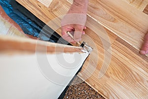 Caucasian man installing wood parquet board during flooring work